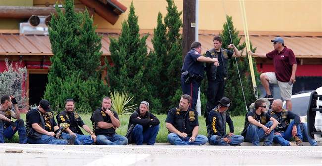 Bikers wait in a line as law enforcement officers investigate the parking lot of a Twin Peaks restaurant Sunday, May 17, 2015, in Waco, Texas. Waco Police Sgt. W. Patrick Swanton told KWTX-TV there were "multiple victims" after gunfire erupted between rival biker gangs at the restaurant. (Rod Aydelotte/Waco Tribune-Herald via AP).