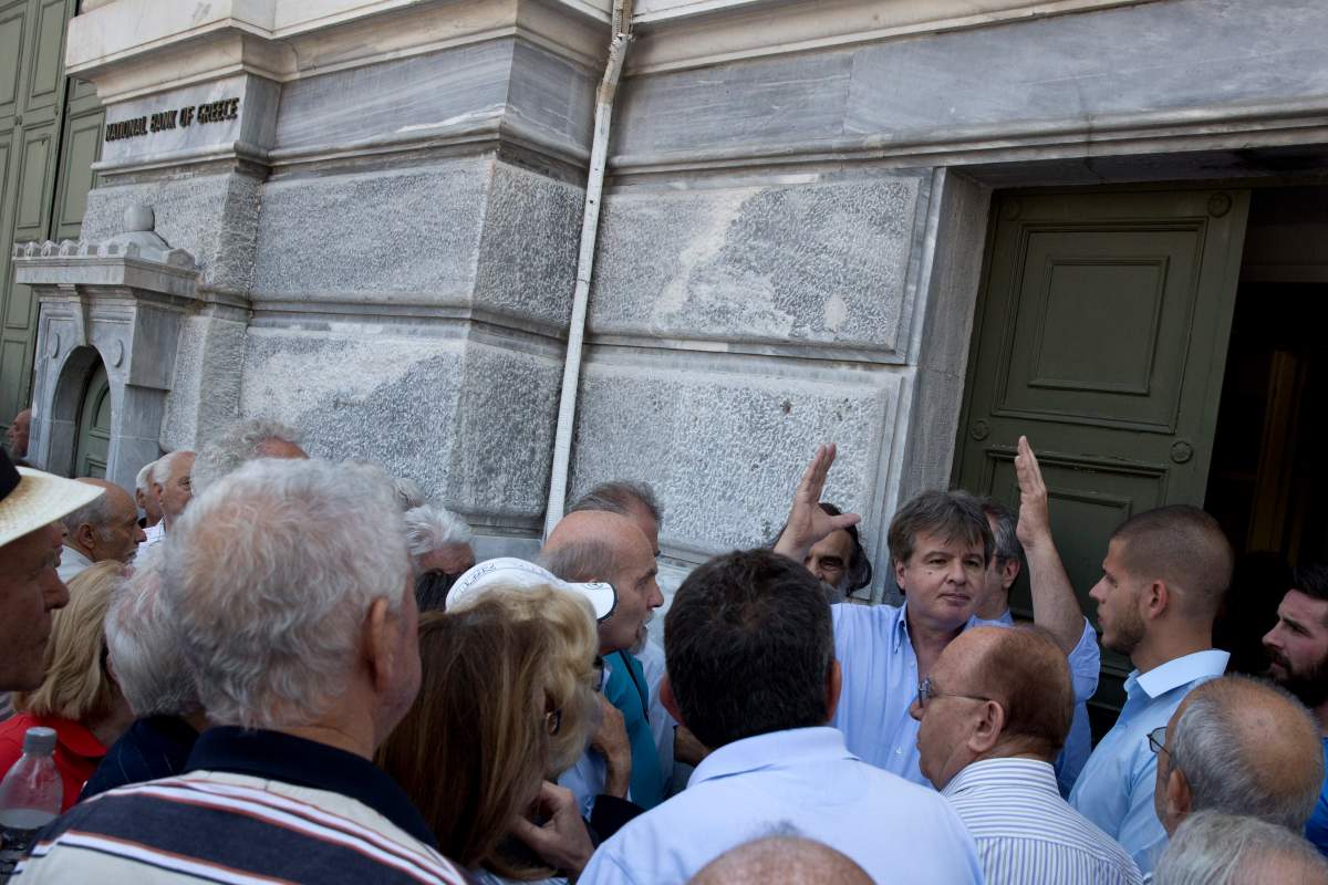 A bank employee explains to pensioners that they will not be able to cash retirement checks at the bank until further notice, outside the National bank of Greece headquarters in Athens, Monday, June 29, 2015.  (AP Photo/Petros Giannakouris)