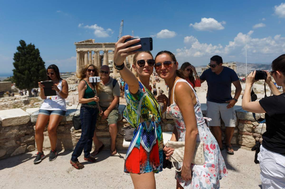 Tourists take snapshots with the ruins of the fifth century BC Parthenon temple on the background in Athens, Monday, June 29, 2015. (AP Photo/Daniel Ochoa de Olza)