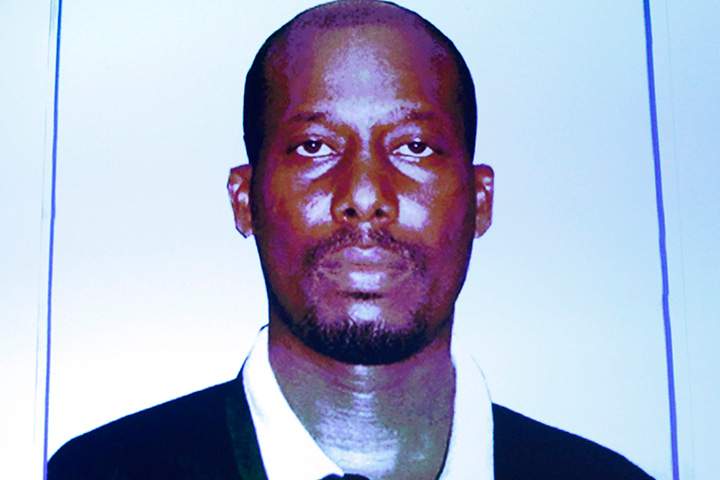 An image of Ali Omar Ader is projected on a screen at RCMP headquarters during a press conference in Ottawa, Friday, June 12, 2015.