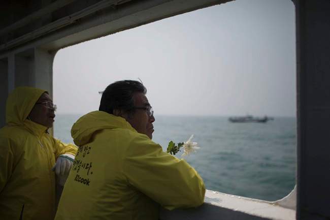 In this April 15, 2015, file photo, a relative of a victim of the ferry Sewol disaster watch the waters with flowers on the deck of a boat during a visit to the site of the sunken ferry, off the coast of South Korea\’s southern island of Jindo. It took divers in South Korea more than three agonizing days just to enter the ferry Sewol after it sank on April 16, 2014.