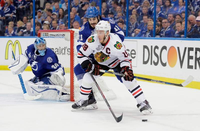 Chicago Blackhawks center Jonathan Toews (19), front, skates around Tampa Bay Lightning center Brian Boyle (11) as goalie Ben Bishop (50), left, defends the net, during the second period in Game 1 of the NHL hockey Stanley Cup Final in Tampa, Fla., Wednesday, June 3, 2015. 