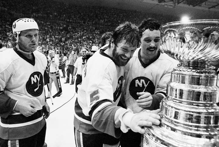 In this May 24, 1980, file photo, New York Islanders captain Denis Potvin (5) reaches out to touch the Stanley Cup trophy as teammate Brian Trottier, right, looks on after the Islanders won the NHL’s Stanley Cup championship by defeating the Philadelphia Flyers 5-4 in overtime in Game 6 at Nassau Coliseum in Uniondale, N.Y.