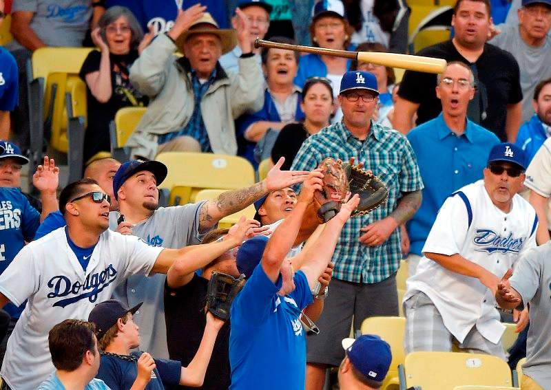 Fans try to catch a bat that Los Angeles Dodgers’ Howie Kendrick lost while at bat during the seventh inning of a baseball game against the St. Louis Cardinals, Sunday, June 7, 2015, in Los Angeles.