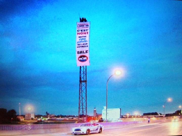 A banner denouncing the reversal of Enbridge’s Line 9B pipeline was erected by activists at the top of a tower in the east end of Montreal on June 15, 2015.