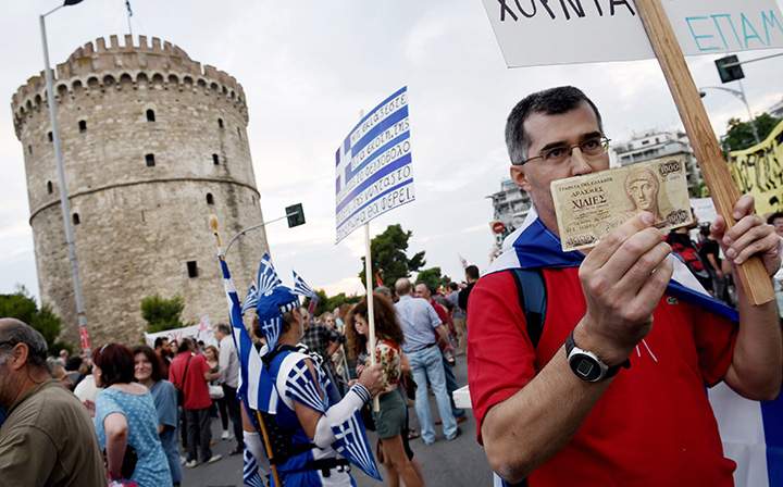 A supporter of the “NO” vote in the upcoming referendum, holds an old 1,000 drachma bank note during a rally in the northern Greek port city of Thessaloniki, Monday, June 29, 2015.
