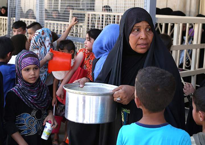 Iraqis, most of them refugees, gather for free food being distributed for Iftar, the meal after fasting, at the Abdul Khader al-Kilani mosque in Baghdad, Iraq, Tuesday, June 23, 2015. 