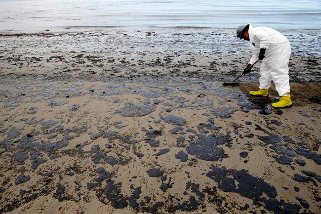 A worker removes oil from the sand at Refugio State Beach, north of Goleta, Calif.
