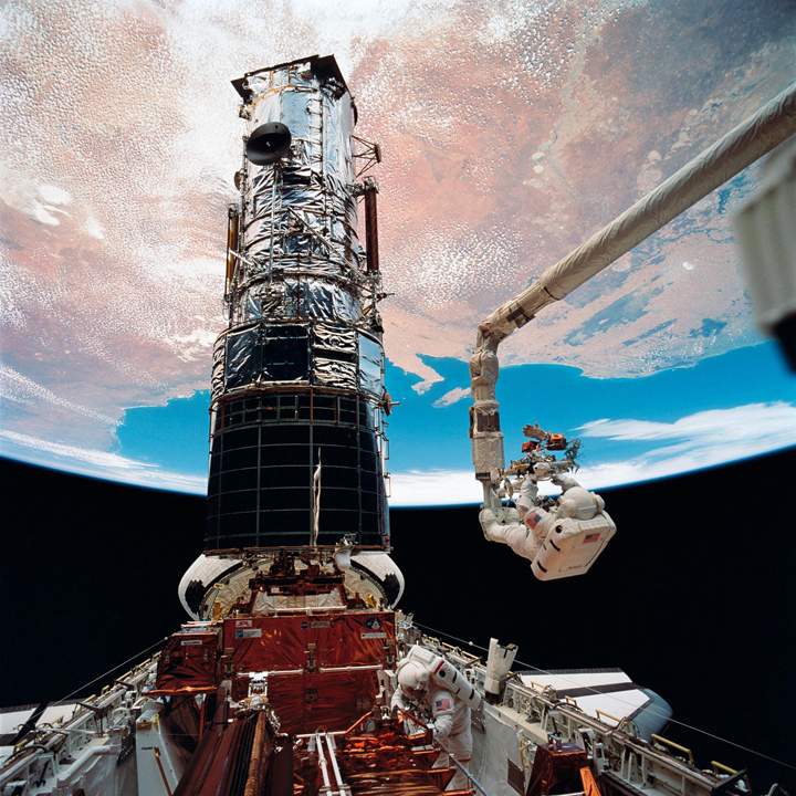 Astronaut Story Musgrave is anchored to the Canadarm during a mission in 1997