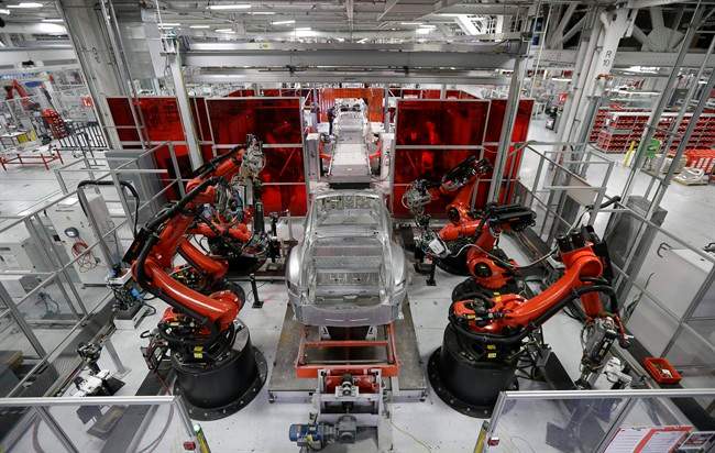 In this May 14, 2015 photo, Kuka robots work on Tesla Model S cars in the Tesla factory in Fremont, Calif.