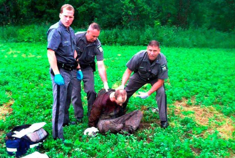 Police stand over David Sweat after he was shot and captured near the Canadian border Sunday, June 28, 2015, in Constable, N.Y. Sweat is the second of two convicted murderers who staged a brazen escape three weeks ago from a maximum-security prison in northern New York. His capture came two days after his escape partner, Richard Matt, was shot and killed by authorities.