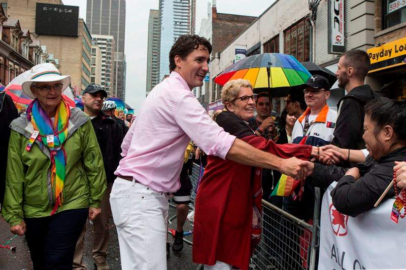 Federal Liberal Leader Justin Trudeau (centre) and Ontario Premier Kathleen Wynne (right) greet the crowd as Wynne’s partner Jane Rounthwaite (left) walks alongside during Toronto’s Pride Parade on Sunday June 28, 2015.