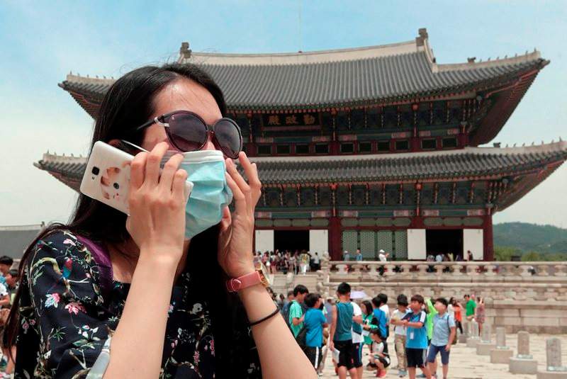 An unidentified Chinese tourist wearing a mask by way of precaution against the Middle East Respiratory Syndrome virus visits Gyeongbok Palace in Seoul, South Korea Monday, June 1, 2015. Authorities say more than 680 people in South Korea are placed in isolation after having contacts with those infected with a virus that has killed hundreds of people in the Middle East. 