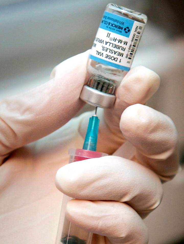 A nurse draws a dose of mumps, measles, and rubella vaccine.