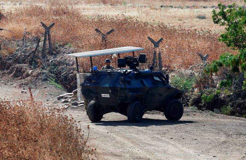 A Turkish soldier stands next to an armoured personnel carrier securing a road near the border with Syria, as seen from the outskirts of the village of Seve, east of the town of Kilis, in southeastern Turkey, Friday, July 24, 2015.
