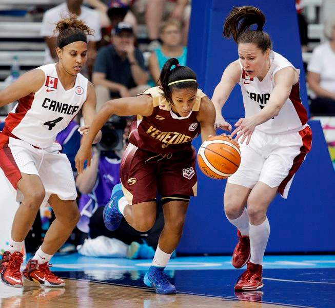 Venezuela's Roselis Silva Serrano, center, breaks away from Canada's Miah Marie Langlois (4) and Kim Gaucher, right, in the first half of a women's preliminary round basketball game at the Pan Am Games Thursday, July 16, 2015, in Toronto. 