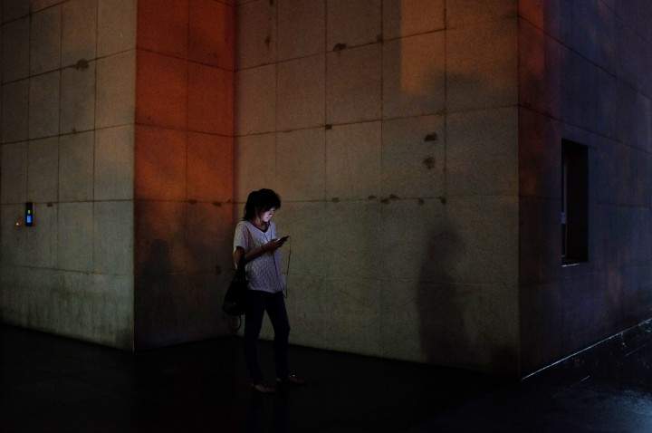 A woman using a smartphone while waiting outside.