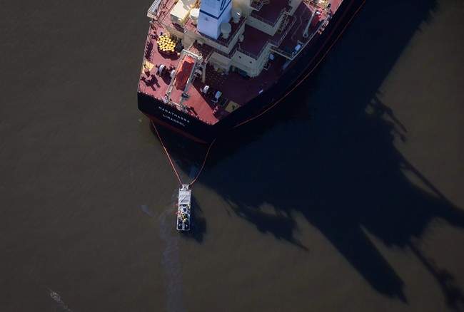 A spill response boat monitors a boom placed around the bulk carrier cargo ship MV Marathassa after a bunker fuel spill on Burrard Inlet in Vancouver, B.C., on April 9, 2015.