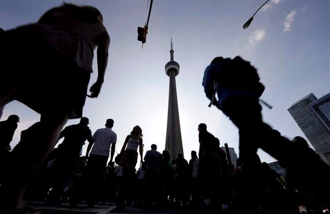 People make their way towards the CN Tower in downtown Toronto on .