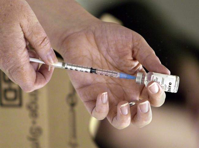 A nurse loads a syringe with vaccine for injection.