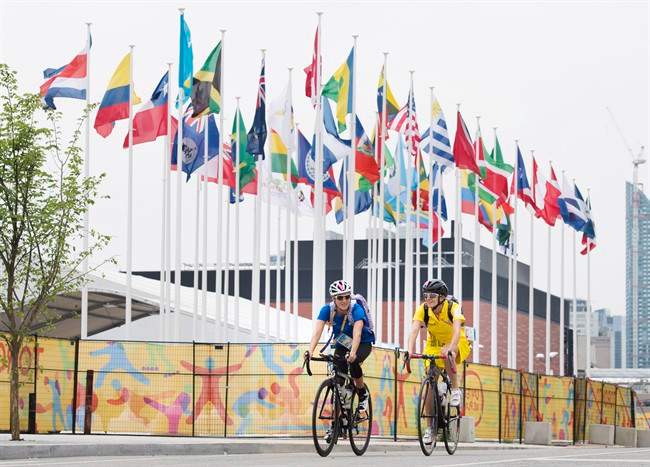 Athletes ride through the athletes' village as the CN Tower stands in the background at the 2015 Pan American Games in Toronto on Thursday, July 9, 2015.