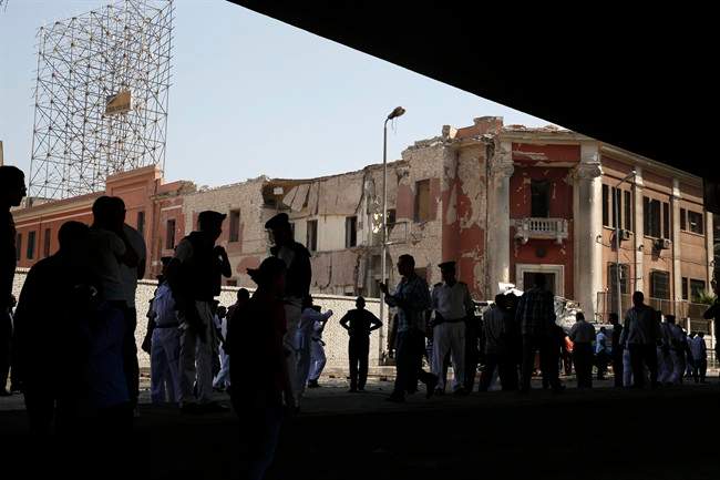 Egyptian policemen stand at the base of the crumbled facade of the Italian consulate following a blast that killed at least one person in Cairo, Egypt, Saturday, July 11, 2015.
