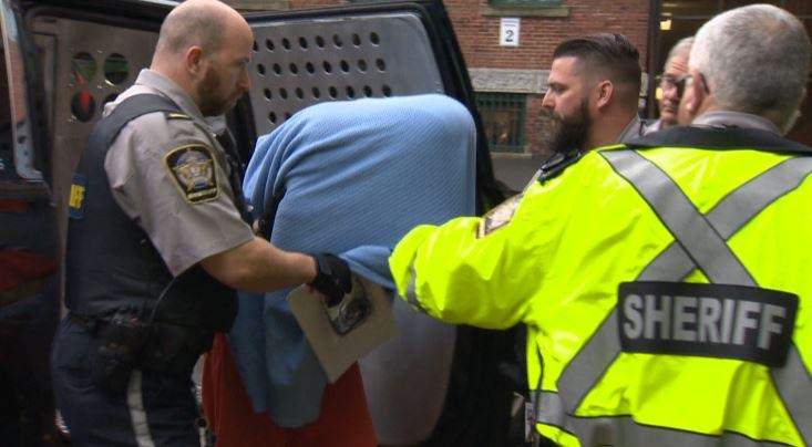 Jimmy Melvin Jr. covers his head with a blanket as he is led into Halifax Provincial Court Monday to face murder charges.
