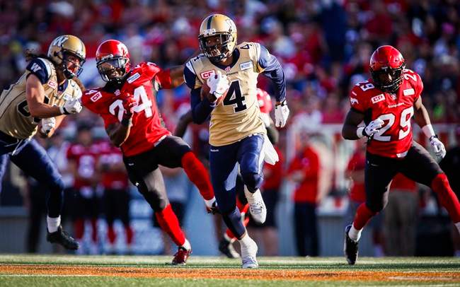 Winnipeg Blue Bombers' Darvin Adams runs the ball in for a touchdown as Calgary Stampeders' Joe Burnett, and Jamar Wall look on during a CFL game in Calgary on Jul. 18, 2015.