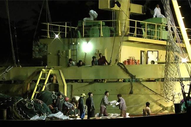FILE – In this Thursday, Nov. 27, 2014 image from video, workers from Myanmar load fish onto a Thai-flagged cargo ship in Benjina, Indonesia. An intricate web of connections separates the fish we eat from the men who catch it, and obscures a brutal truth: Your seafood may come from slaves.