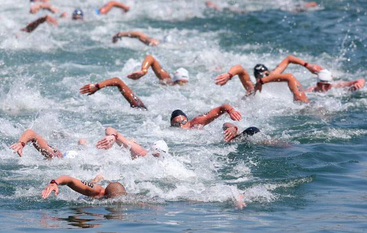Richard Weinberger #86 of Canada and Damien Cattin-Vidal #32 of France lead a group of swimmers during the Open Water Swimming Men's 10k race on day three of the 15th FINA World Championships at Moll de la Fusta on July 22, 2013 in Barcelona, Spain.