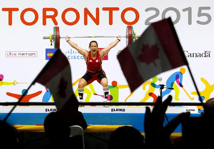 Canada’s Marie-Josee Ares-Pilon is seen through Canadian flags as she attempts a lift during the women’s 60kg weightlifting competition at the Pan Am Games, Tuesday, July 14, 2015, in Oshawa, Ontario.