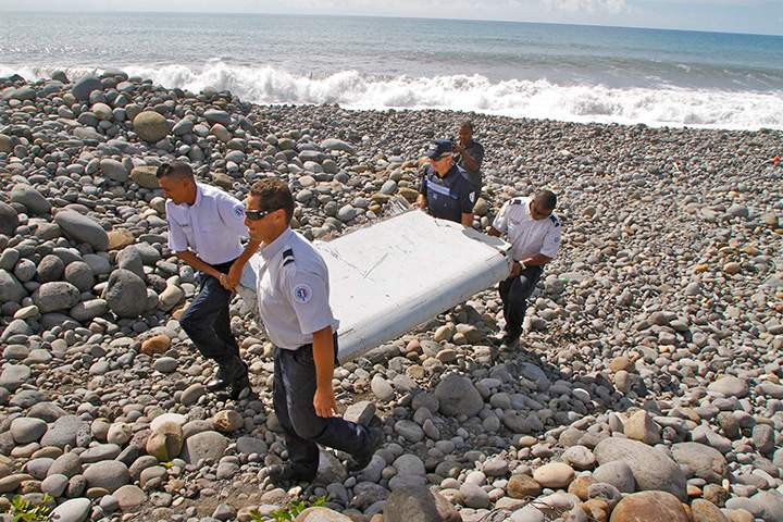 In this photo dated Wednesday, July 29, 2015, French police officers carry a piece of debris from a plane in Saint-Andre, Reunion Island.