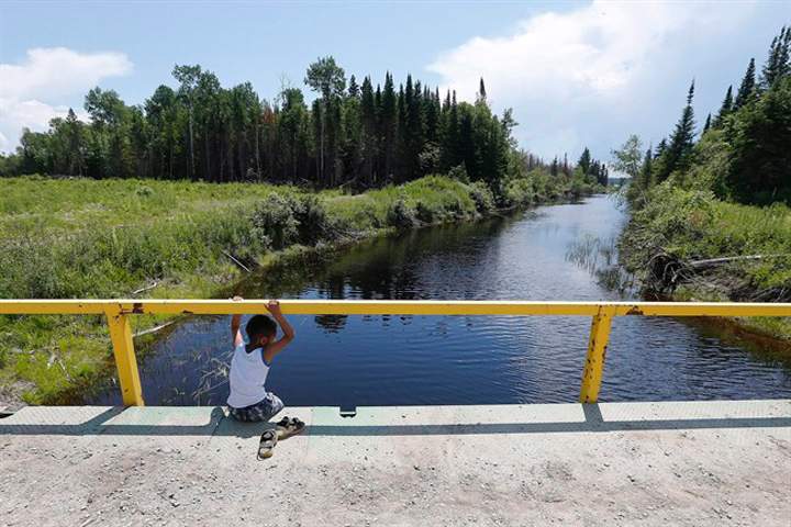 A boy from the Shoal Lake 40 First Nation sits on a bridge over a channel on  June 25.