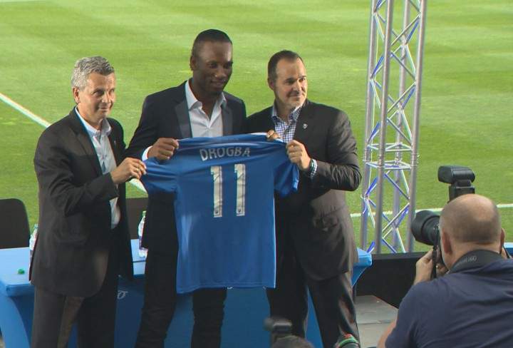 The Montreal Impact’s new star forward, Didier Drogba, holds up his jersey with the iconic #11.