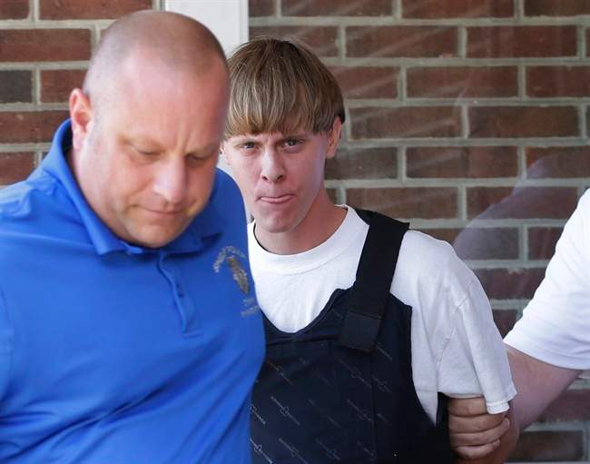FILE - In this June 18, 2015, file photo, Charleston, S.C., shooting suspect Dylann Storm Roof, center, is escorted from the Sheby Police Department in Shelby, N.C. FBI director James Comey says Roof, the gunman in the Charleston church massacre should not have been allowed to purchase the gun used in the attack, and on July 10 attributed the problem to incomplete and inaccurate paperwork related to an arrest of Roof weeks before the shooting. (AP Photo/Chuck Burton, File).