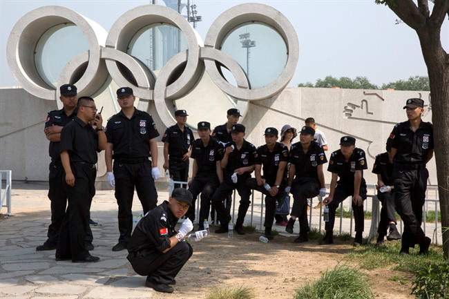 In this photo taken Sunday, May 31, 2015, Chinese security personnel rest near the Olympic rings near the Bird's Nest National Stadium in Beijing.