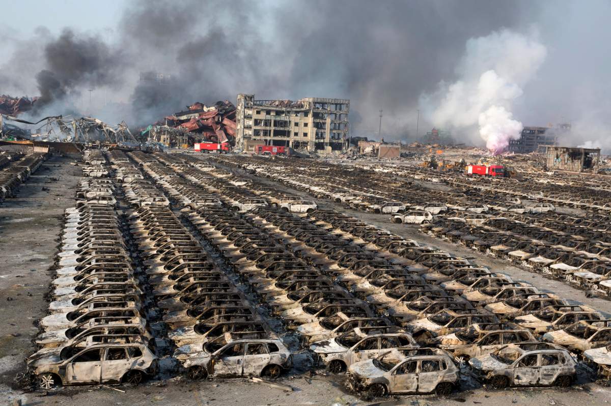 Smoke billows out from the site of an explosion that reduced a parking lot filled with new cars to charred remains at a warehouse in northeastern China’s Tianjin municipality, Thursday, Aug. 13, 2015.