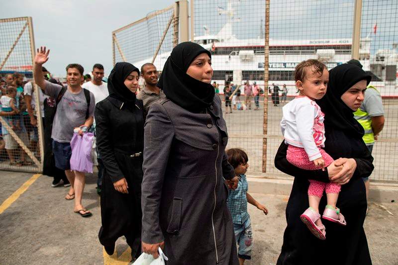 Migrants and refugees walk to board an Athens-bound ferry at the southeastern island of Kos, Greece, Saturday, Aug. 15, 2015. The International Organization for Migration said the number of migrants and asylum-seekers who have crossed the Mediterranean to Europe this year will pass the quarter-million mark by the end of the month, more than half of them arriving in Greece.