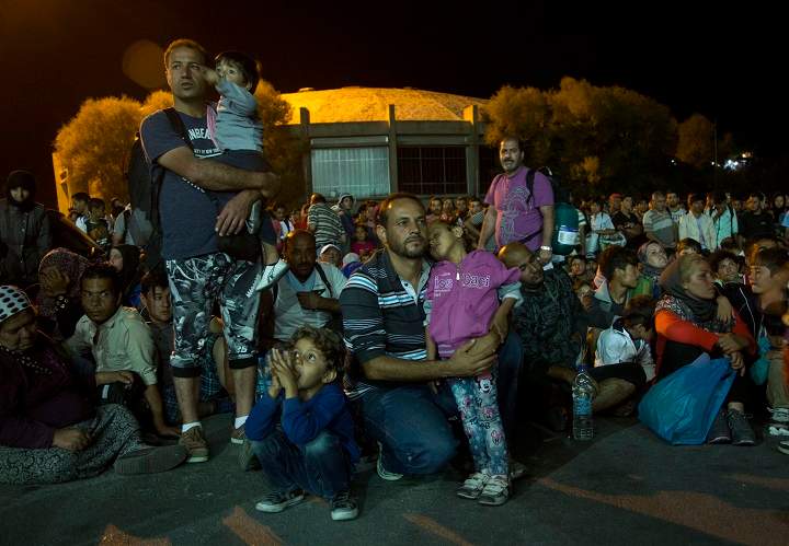 In this Sunday, Aug. 23, 2015 photo, a Syrian migrant child sleeps in the arm of her father before heading to Athens at the port town of Mytilini after crossing the Aegean from Turkey, on the southeastern Greek island of Lesbos. Some 2,500 migrants departed for Athens as Greece this year has been overwhelmed by record numbers of migrants arriving on its eastern Aegean islands, with more than 160,000 landing so far. (AP Photo/Visar Kryeziu).