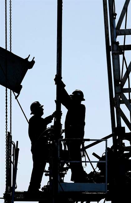 A service rig crew performs maintenance and repair work on an oilfield pumpjack and well head site in Alberta on June 20, 2007. 