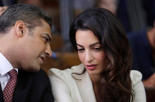 Canadian Al-Jazeera English journalist Mohamed Fahmy, left, talks to human rights lawyer Amal Clooney before his verdict in a courtroom in Tora prison in Cairo, Egypt, Saturday, Aug. 29, 2015.