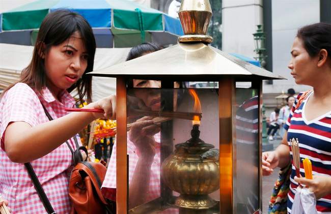 In this Aug. 26, 2015, file photo, worshippers light sticks of incense at the Erawan Shrine at Rajprasong intersection, in Bangkok, Thailand. (AP Photo/Penny Yi Wang, File).