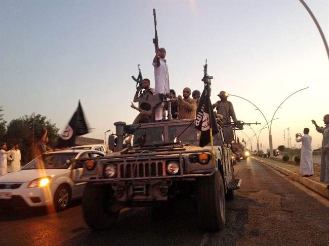 FILE - In this June 23, 2014, file photo, fighters from the Islamic State group parade in a commandeered Iraqi security forces armored vehicle down a main road at the northern city of Mosul, Iraq. 