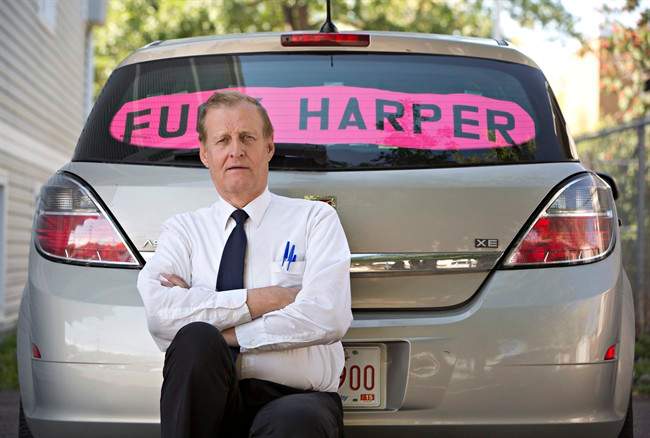 Rob Wells stands with his Steven Harper sign he put in his vehicle's rear window in Edmonton Alta, on Wednesday Aug 19, 2015. Wells has been fined $543 by police for having the sign in his car. 
