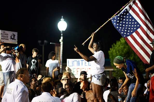 Demonstrators protest during a march on August 8, 2015 at the Ferguson Police Department in Ferguson, Missouri.  The crowd worked its way along one of the avenues hit by fierce rioting last November when a court decided not to indict the white officer who shot 18-year-old Brown.