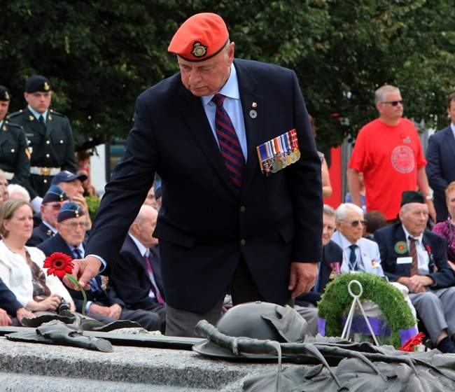 Veterans Affairs Ombudsman Guy Parent lays a flower at the Tomb of the Unknown Soldier, during a commemoration ceremony of the 70th anniversary of the end of the Second World War in the Far East, or V-J Day (Victory Over Japan) at the National War Memorial in Ottawa on Saturday, August 15, 2015. 