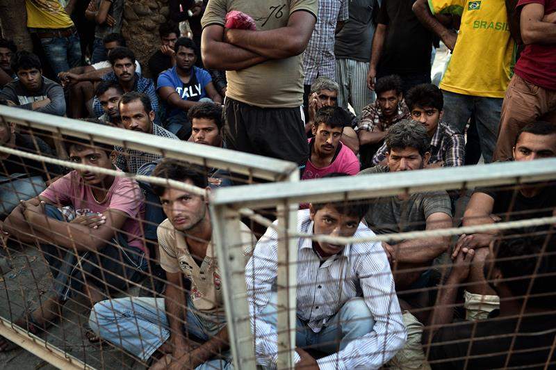 Migrants wait outsie the police station which serves as their registration center in the town of Kos at the southeastern Greek island of Kos, on August 15, 2015.