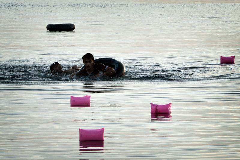 Syrian migrants swim towards the beach after arriving on an overcrowded dinghy to the Greek island of Kos, on August 15, 2015.