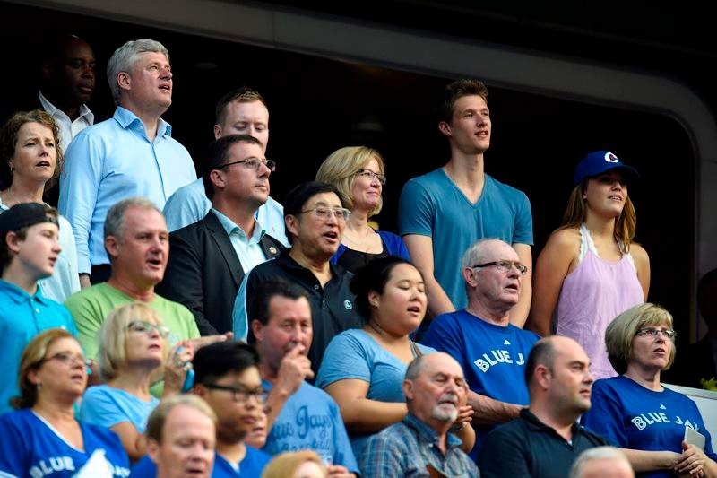 Conservative Leader Stephen Harper and his family sing the national anthem as the Toronto Blue Jays prepare to take on the Cleveland Indians during American League baseball action in Toronto on Monday, August 31, 2015.