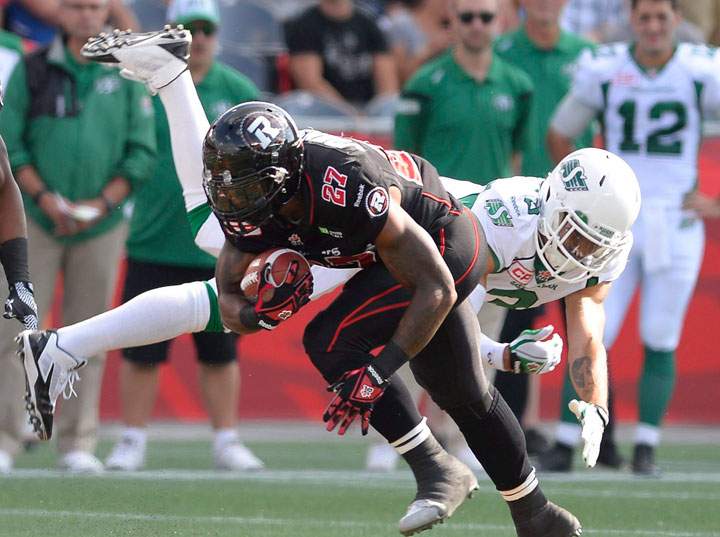 Ottawa Redblacks' Jeremiah Johnson, left, keeps the ball away from a flying Saskatchewan Roughriders' Macho Harris during first half CFL action in Ottawa on Sunday, August 30, 2015.